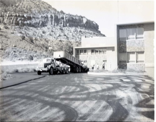 Paving of employee parking area, Mission 66 Visitor Center and Museum. Truck pouring hot mix at loading dock area.