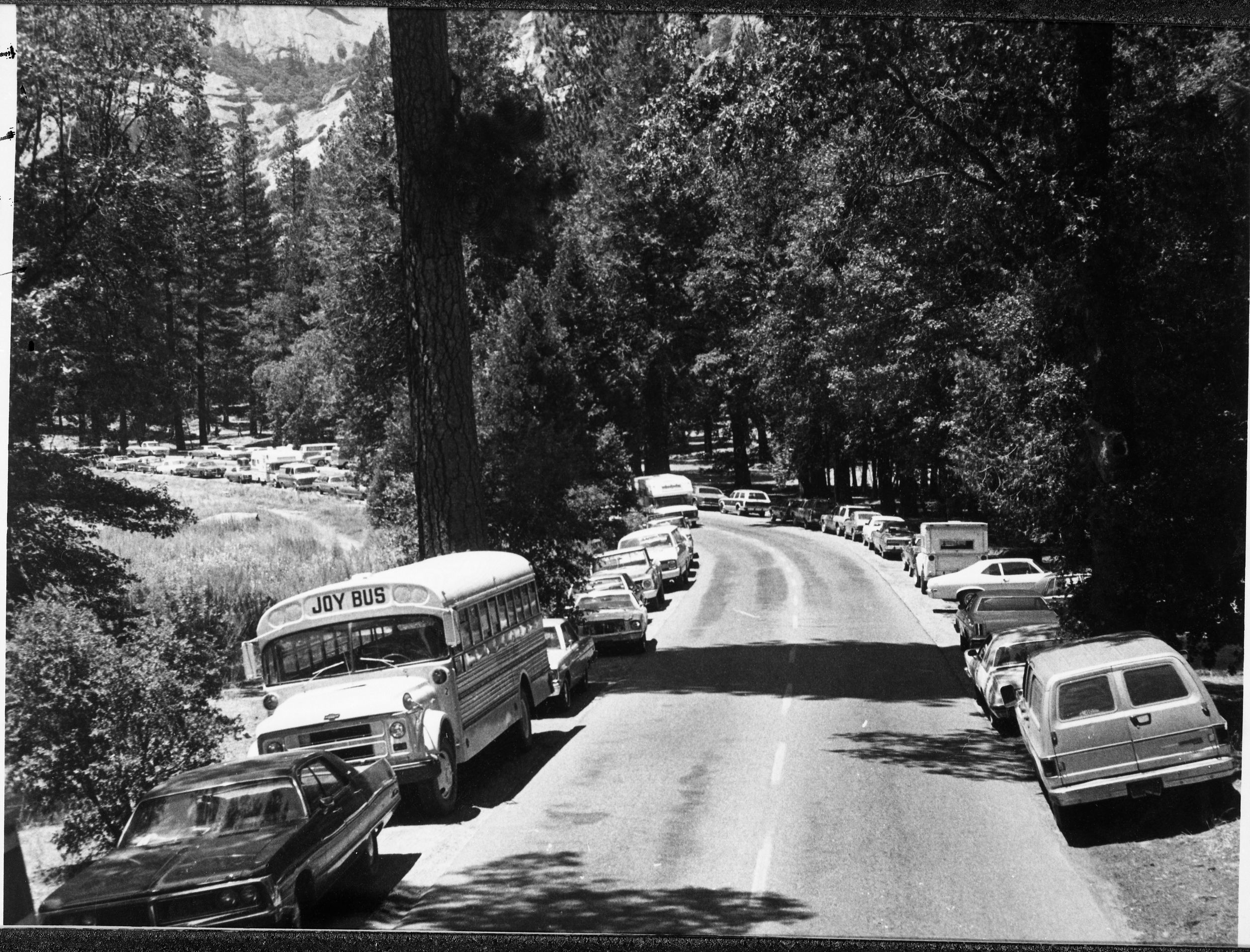 Vehicles parked along road to Ahwahnee Hotel, Yosemite Valley. Published in "Crisis in Yosemite."