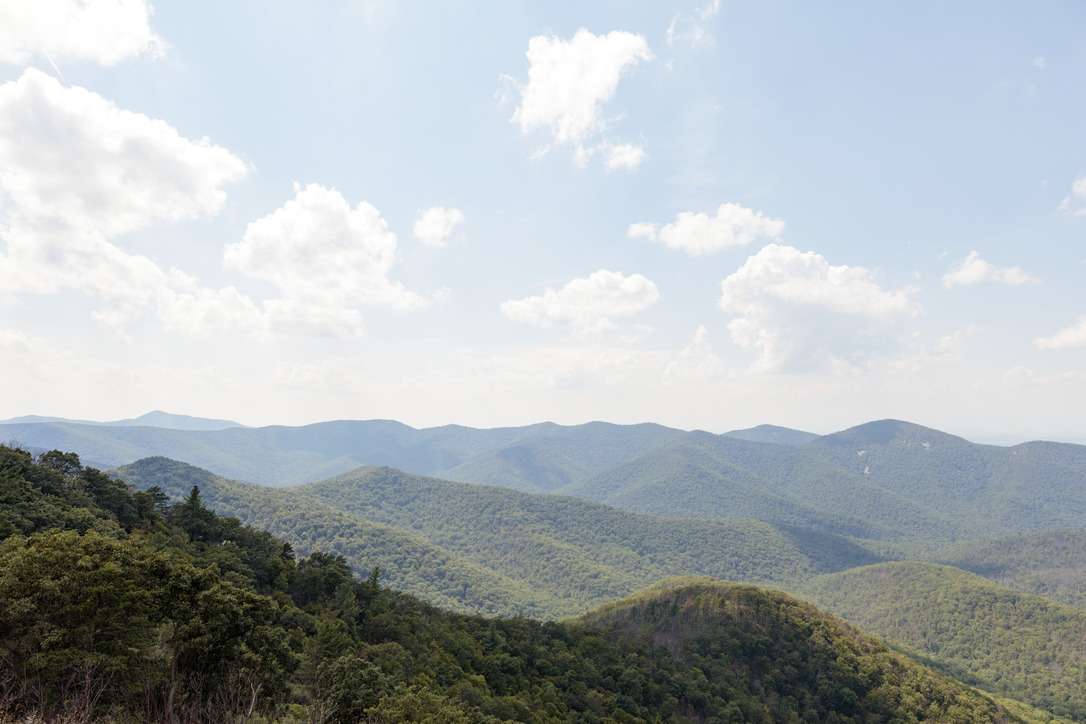 A whitish haze dulls the view of more distant tree covered mountain ridges.