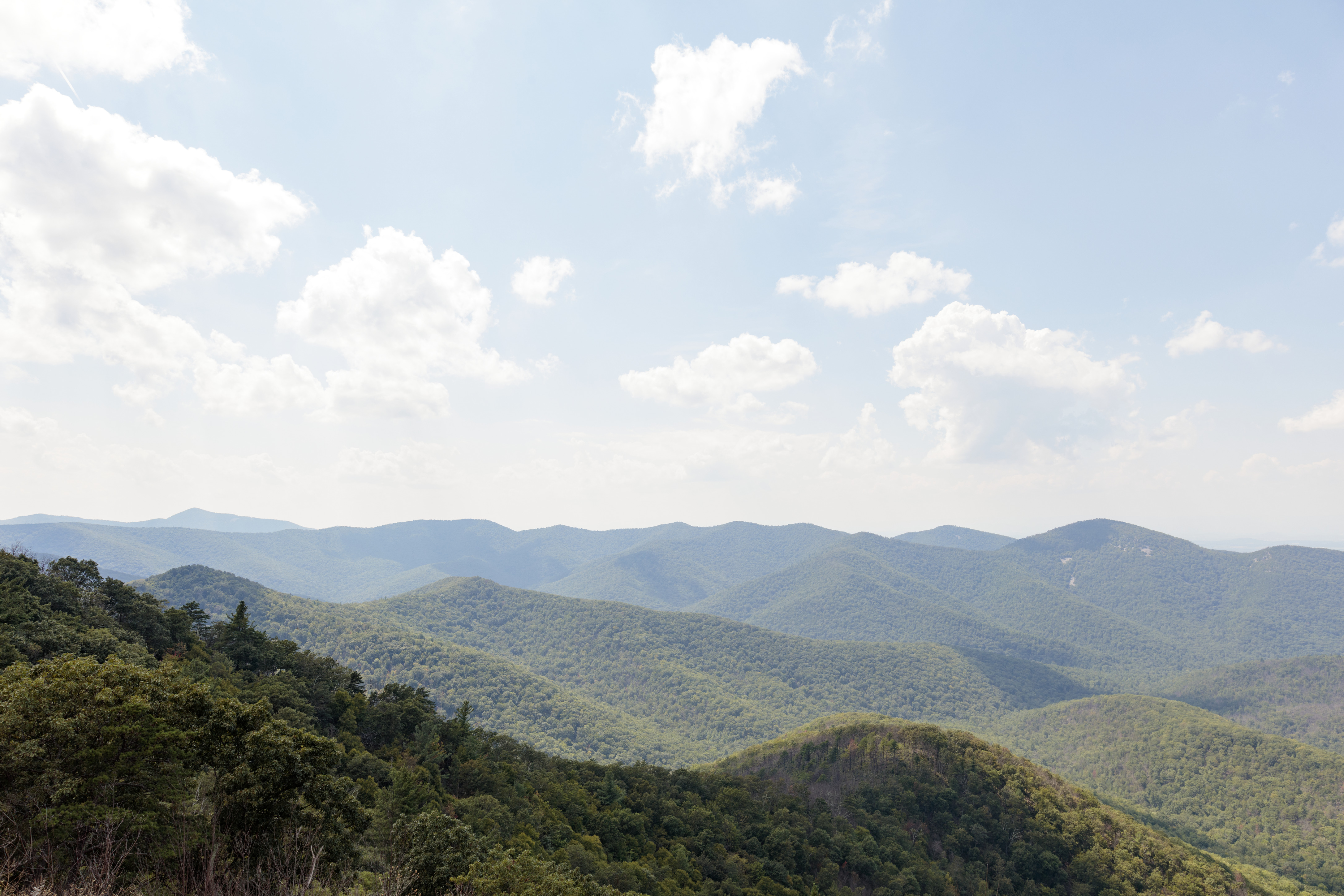 A whitish haze dulls the view of more distant tree covered mountain ridges.