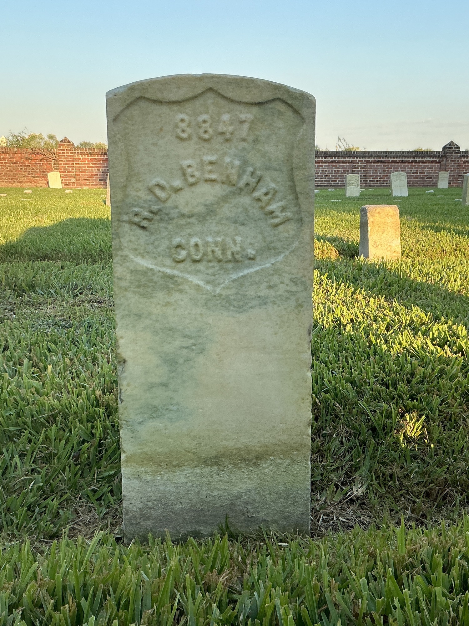 Front of historic upright marble headstone with recessed shield face.