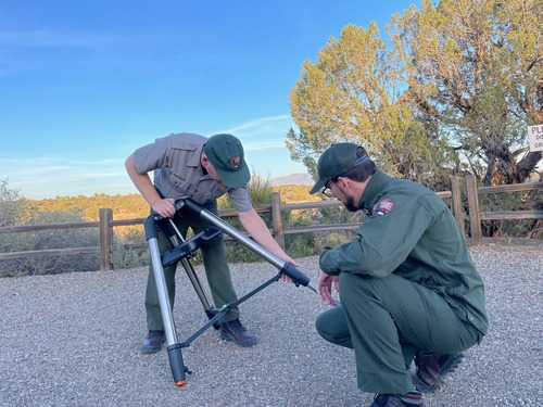Two people outside putting together a tripod.