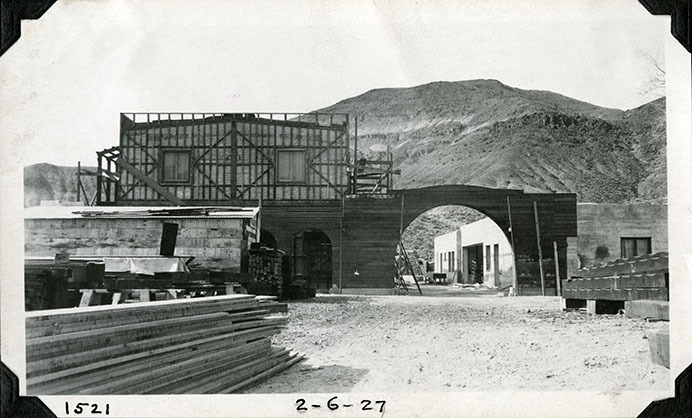 This is an historic black and white photograph from the Scotty's Castle Historic Photograph Collection, Death Valley National Park of Scotty's Castle Main House looking west. Highlights Enclosed Patio arch wall connecting to Annex. February 6, 1927. Photographed by Mat Roy Thompson.