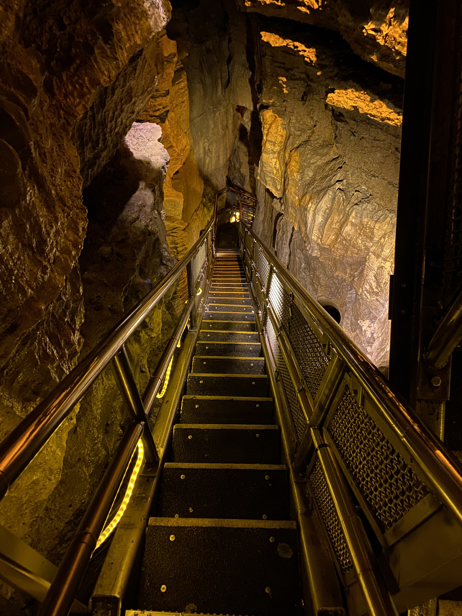 A large metal staircase travels down in the cave.