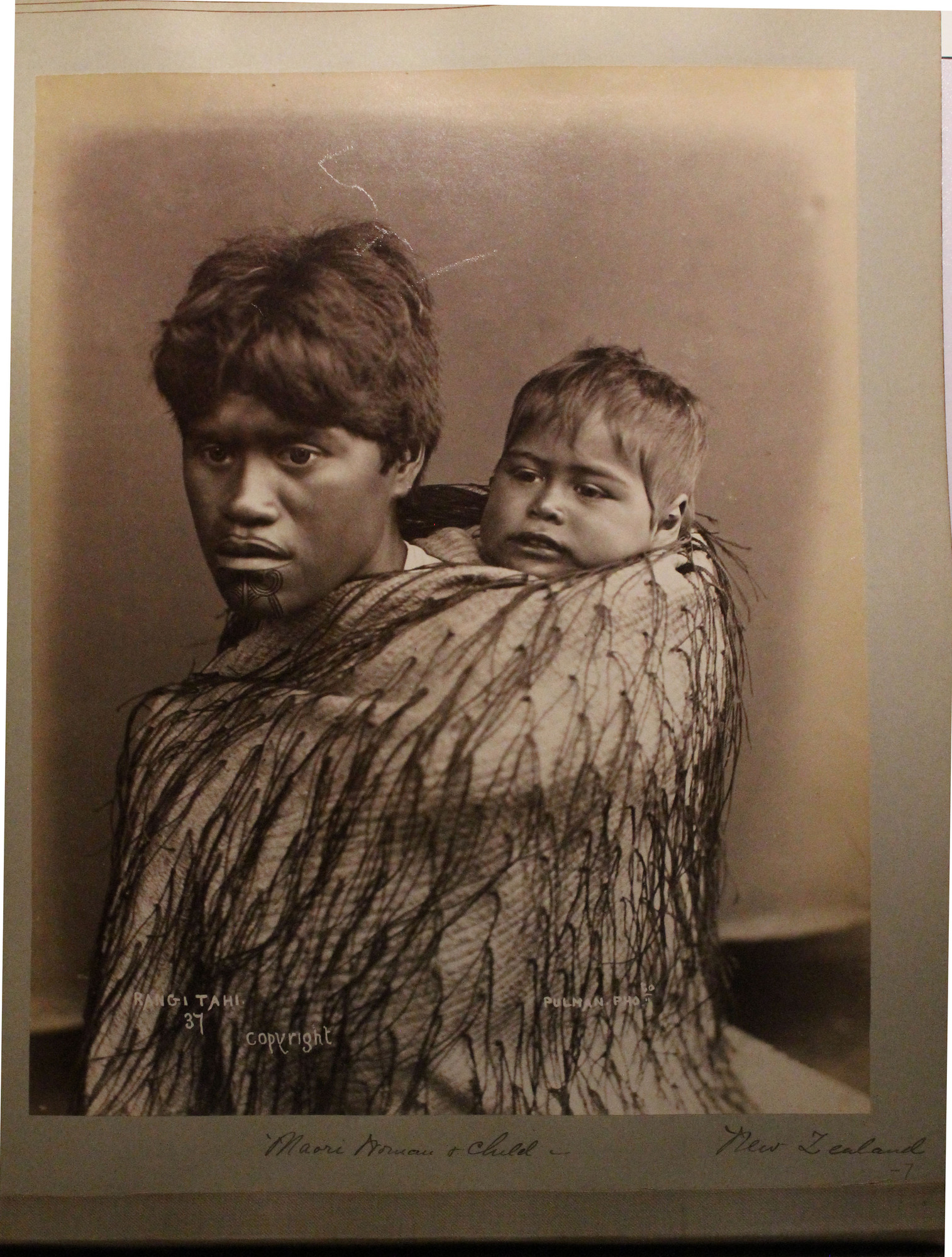 Maori woman and baby posed in traditional cloak.