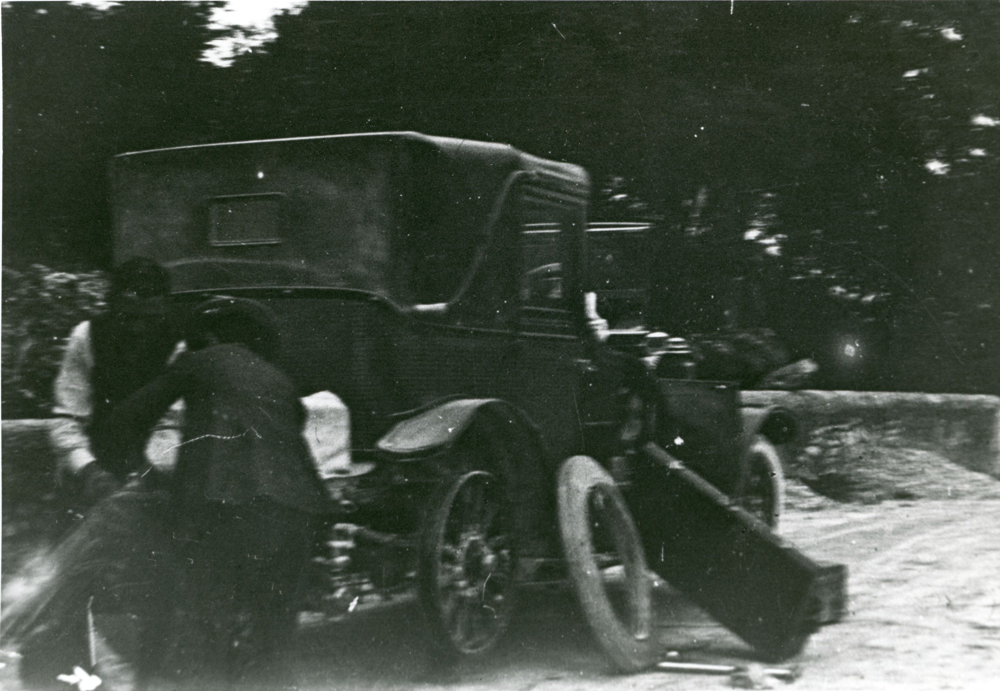 Two men on the side of a road changing a car tire.