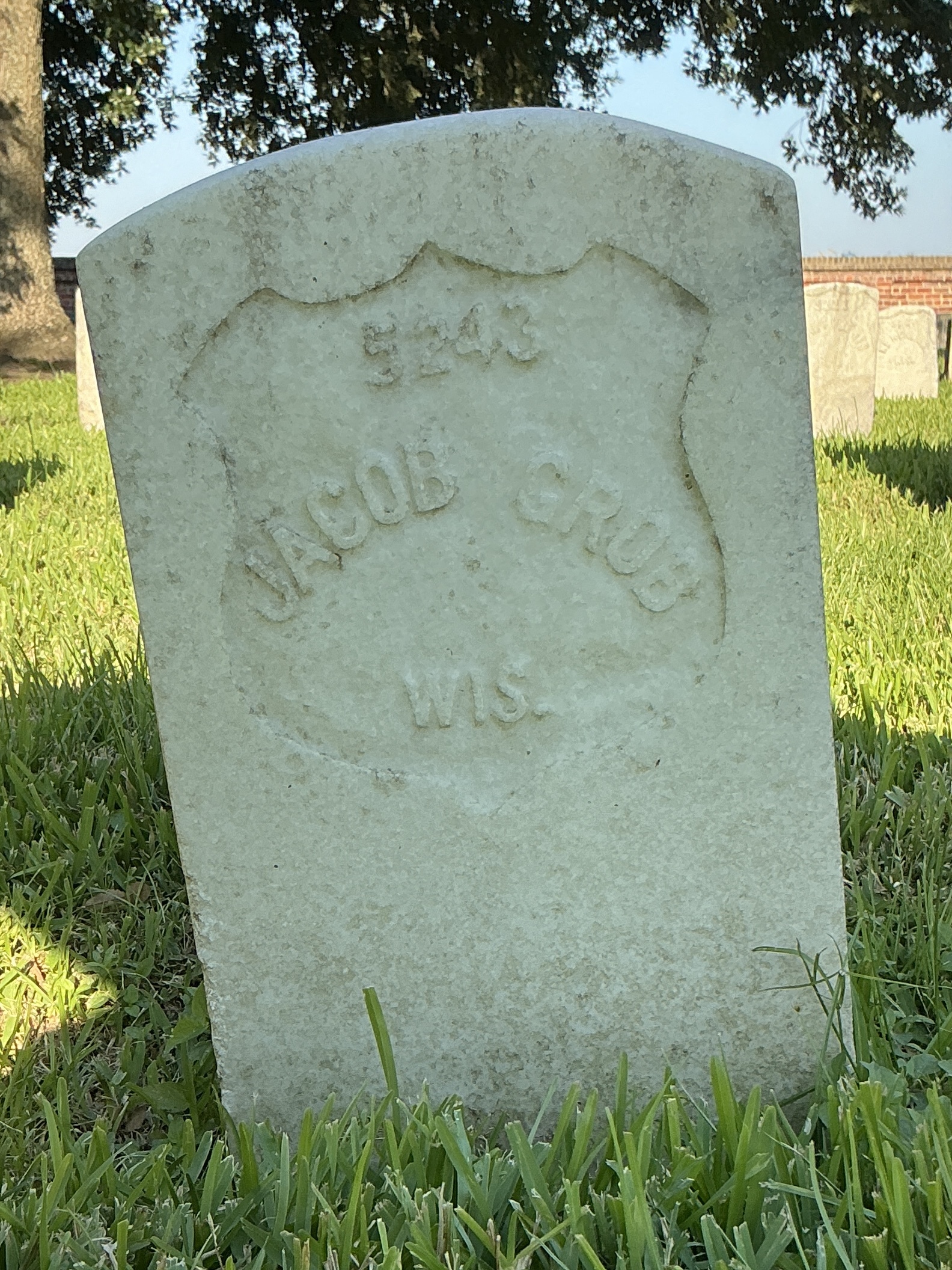 Front of historic upright marble headstone with recessed shield face.