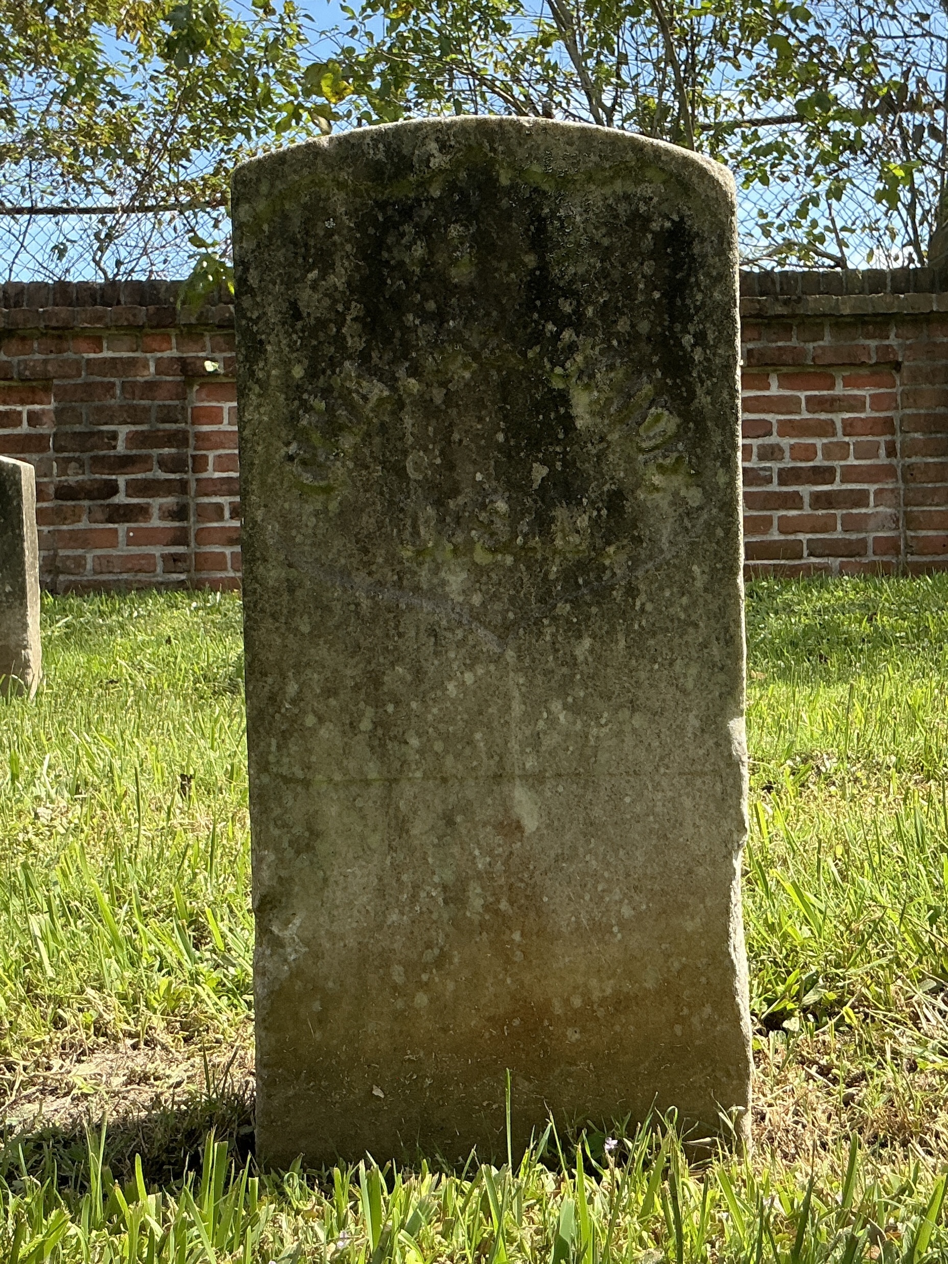 Front of historic upright marble headstone with recessed shield face.