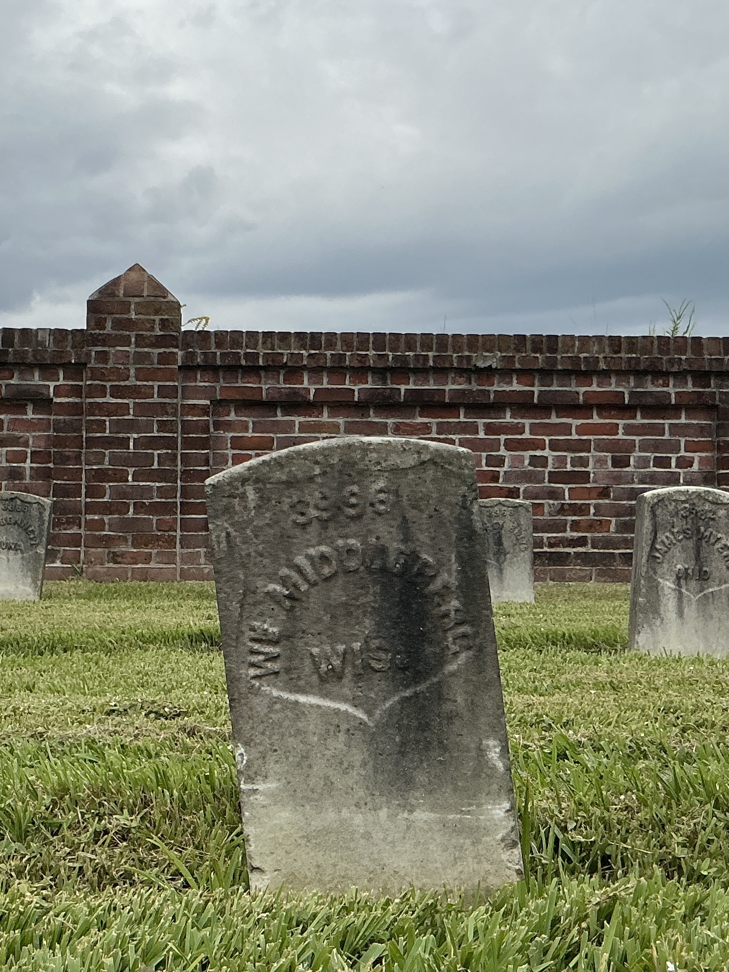 Front of historic upright marble headstone with recessed shield face.