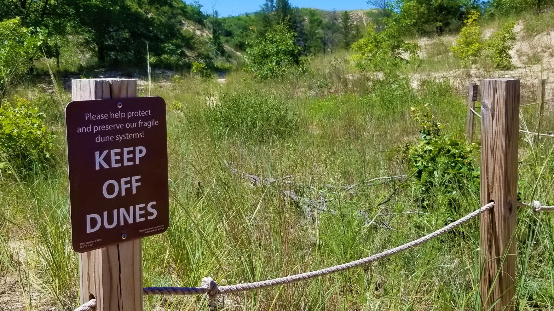 An image of a sign that reads "Keep off dunes."