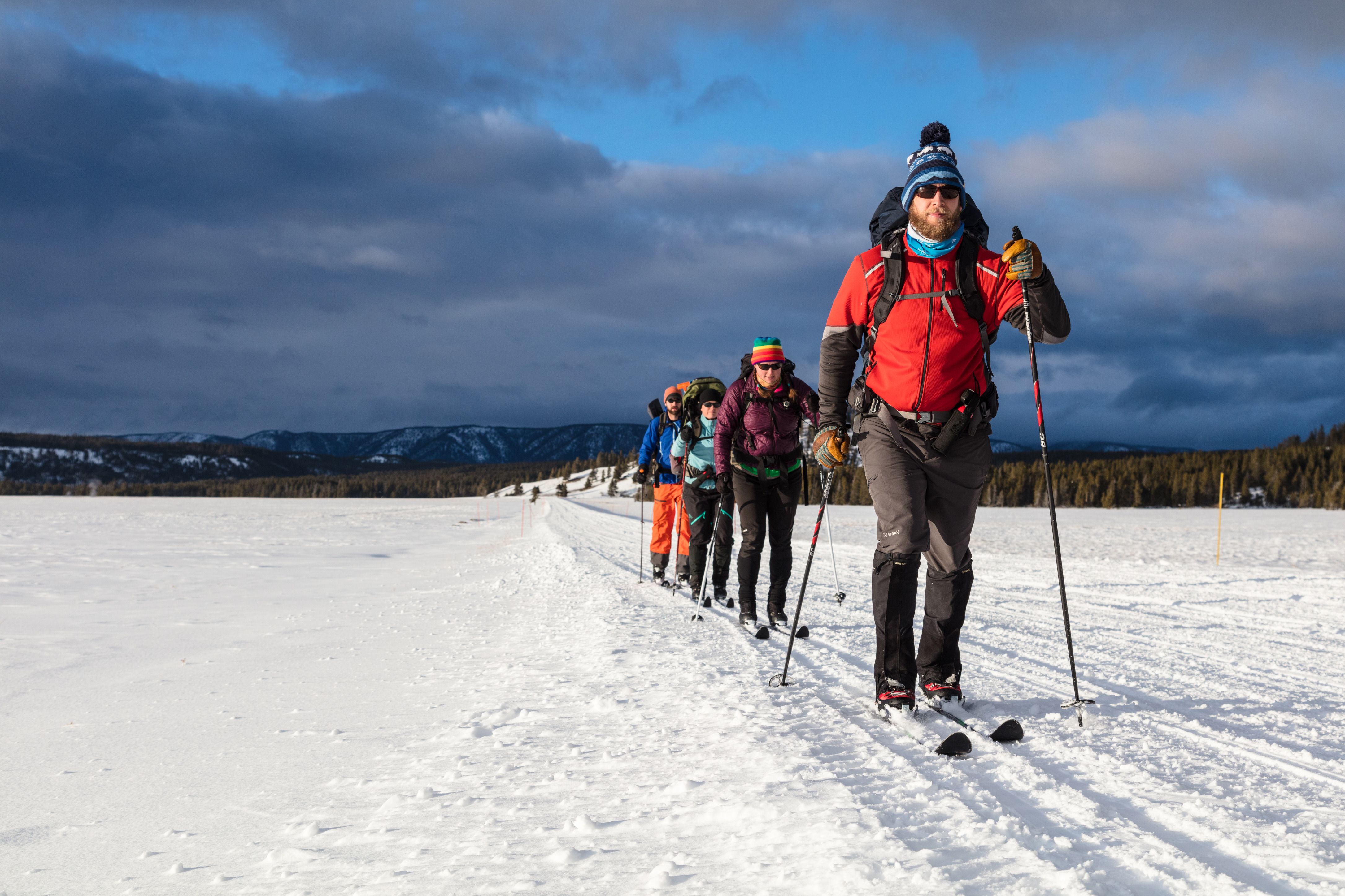 People with backpacks on skiing along snow covered road