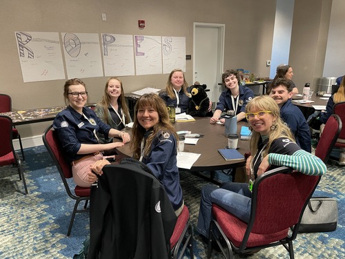 A group of people sitting around a table in a conference room posing for a picture.