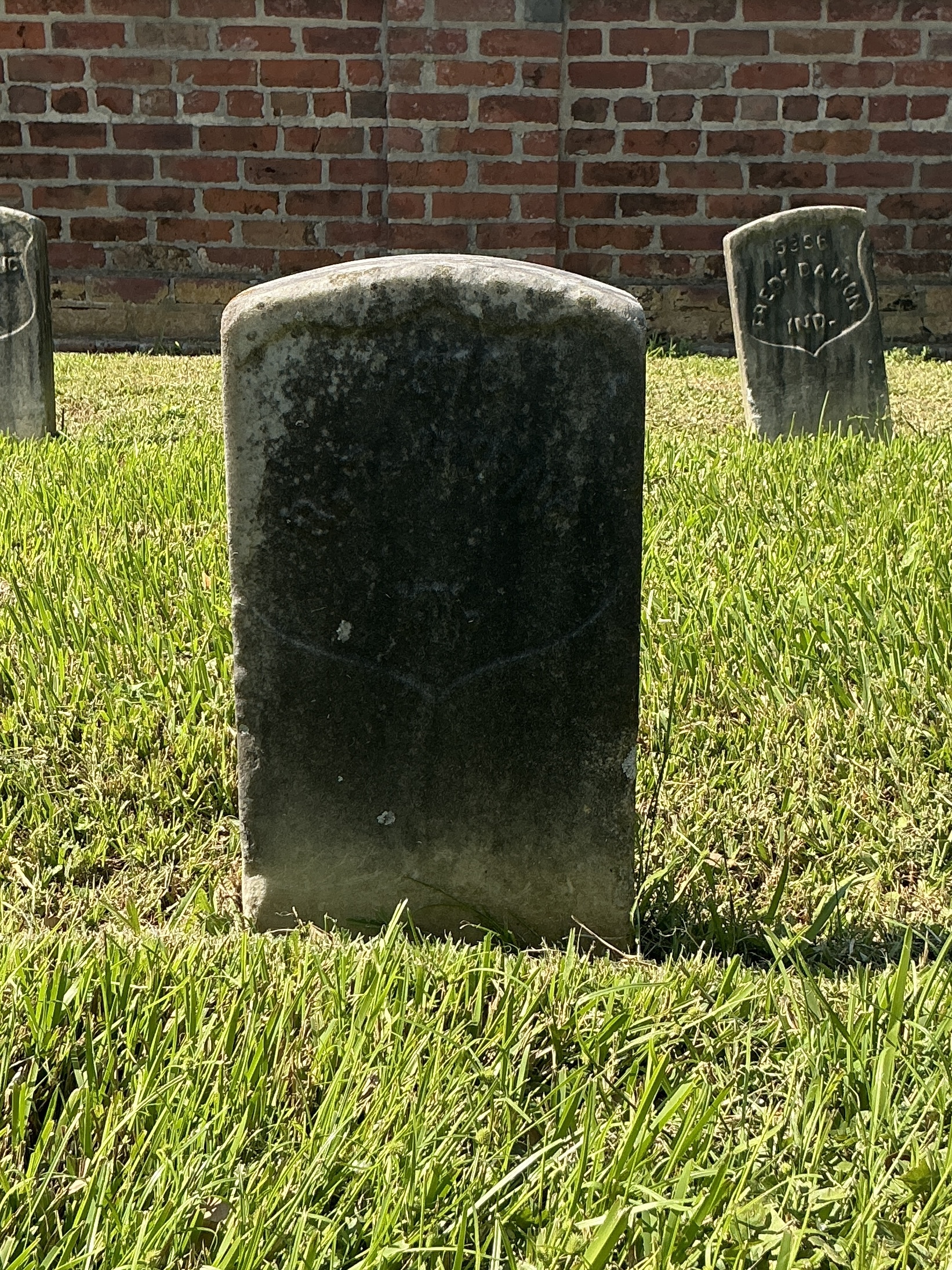 Front of historic upright marble headstone with recessed shield face.