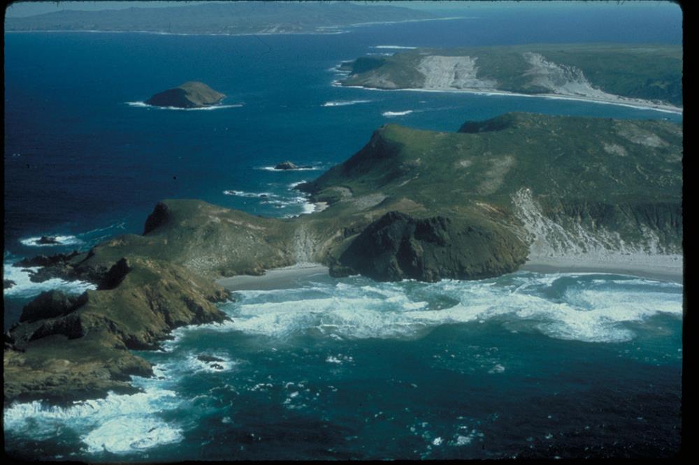Lester and Harris Points on San Miguel Island with Cuyler Harbor, Prince Island and the western end of Santa Rosa Island in the background. White water where waves are breaking on rocky shoreline in foreground.