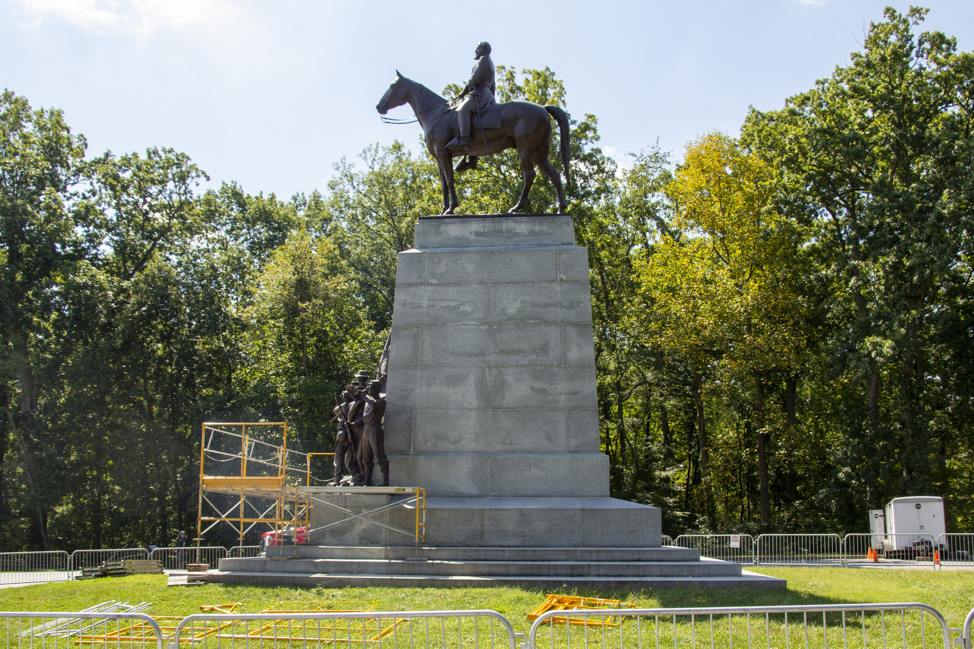 A profile view of a Civil War statue with tall stone base, soldiers on the bottom and an officer on horseback on top. The statue is surrounded by scaffolding 