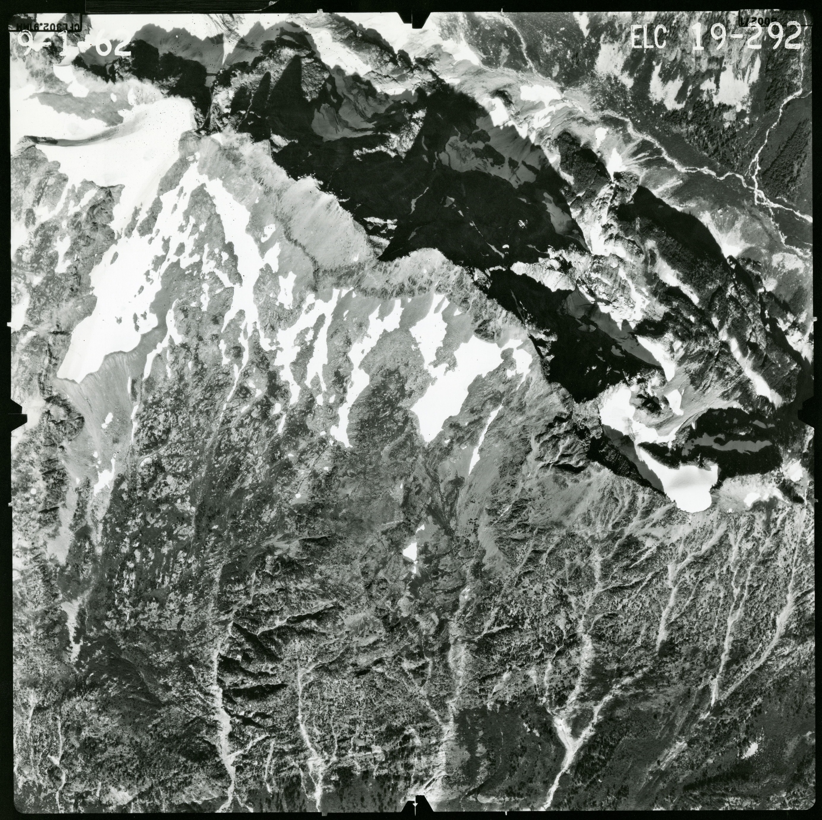 Black and white aerial photograph of glaciated mountain peaks and valleys.