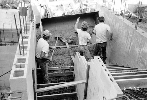 Men shoveling gravel/cement during the construction of headquarters addition.