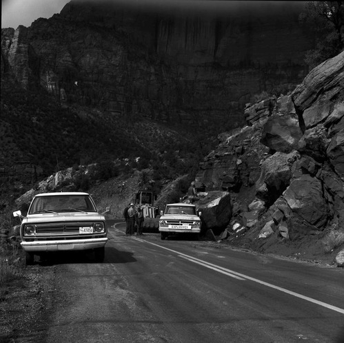 Rock removal from Pine Creek road (Zion-Mt. Carmel Highway--State Route 9), road crew and equipment near boulder in road.