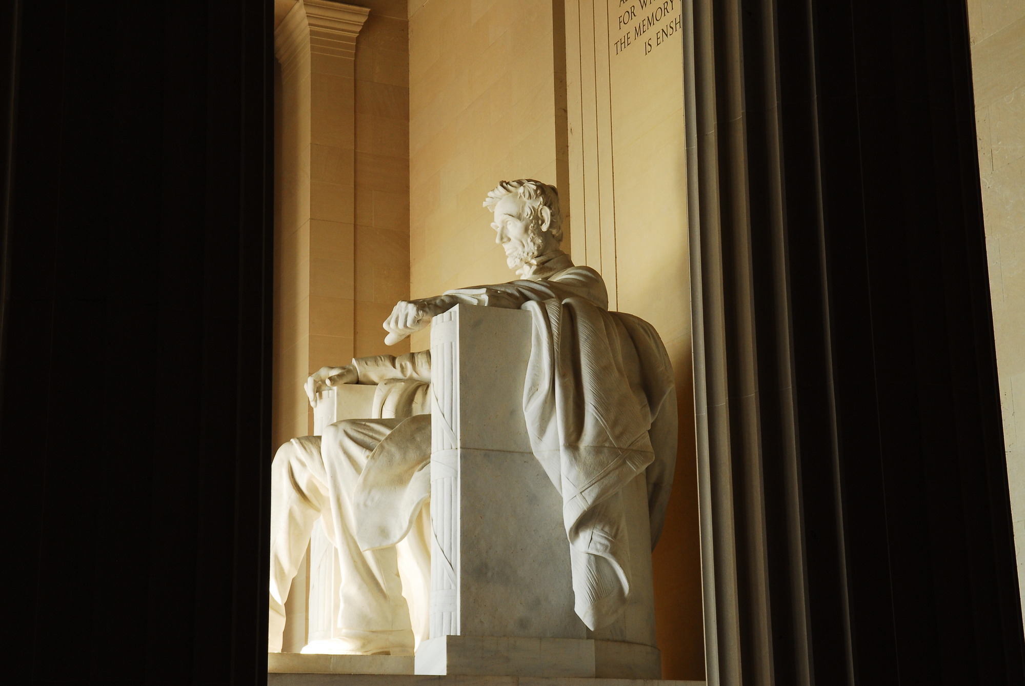 The statue of Abraham Lincoln sitting in a stair through marble columns inside the Lincoln Memorial