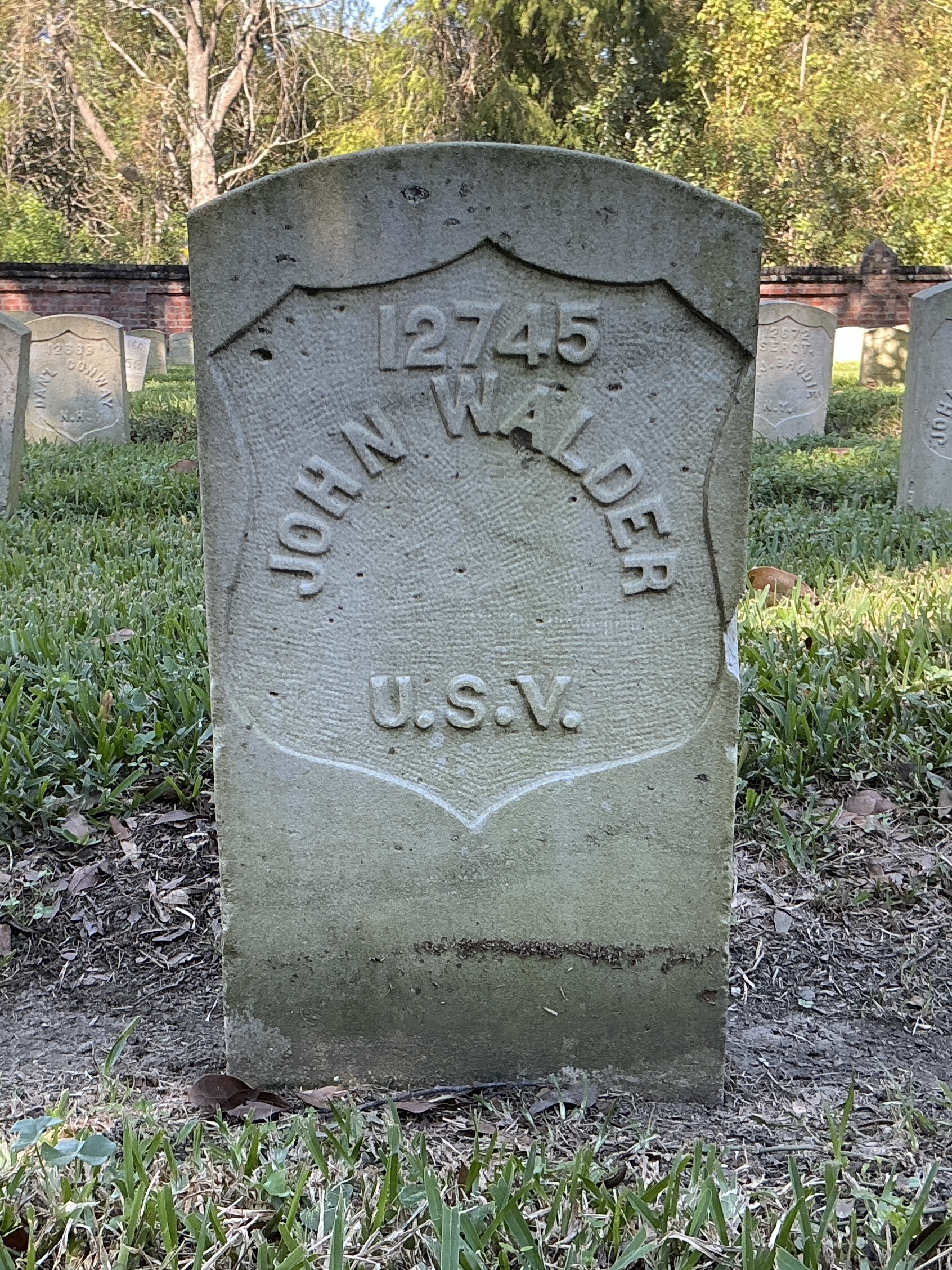 Front of historic upright marble headstone with recessed shield face.