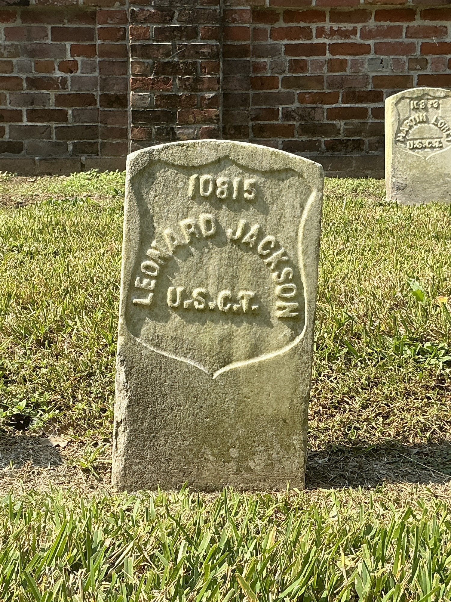 Front of historic upright marble headstone with recessed shield face.