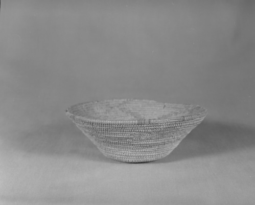 Private Collection. Object: Miwok basket. Dimensions: 7 1/4 x 2 1/2". Materials: Split shoots, bracken fern root. Technology: Interlocking stitch, three rods, fag ends trimmed on workface, moving ends trimmed on interior. Clockspring start filled by jamming whole stick in start. Original rim is missing. Encrusted with acorn mush. Collection History: Purchased from Maggie Longfellow's mother, also known as Mrs. Lonfellow Poncho. Photographed by Michael Dixon. Catalogued by Craig Bates and Barbara Beroza. Yosemite Collections, National Park Service.