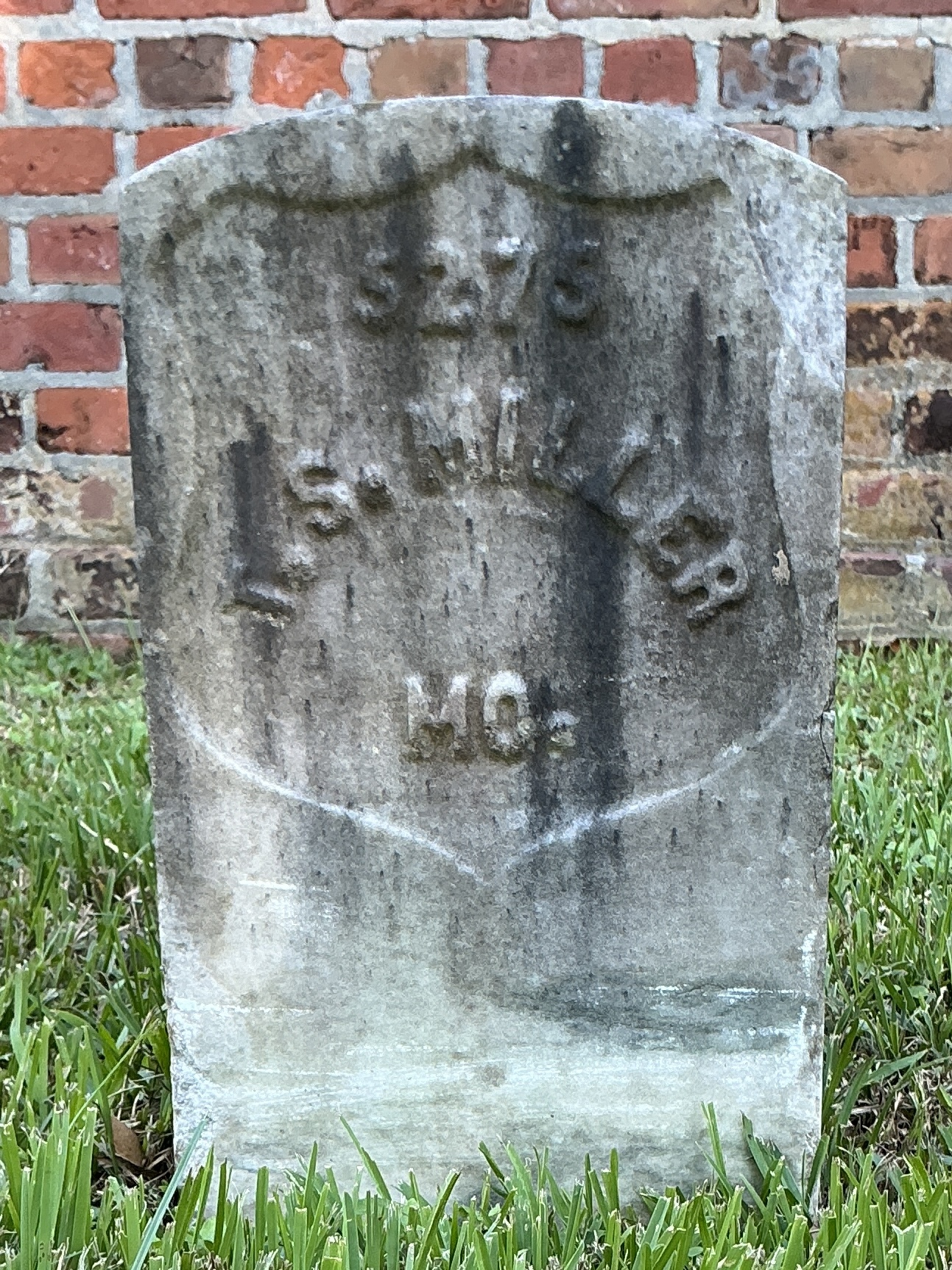 Front of historic upright marble headstone with recessed shield face.