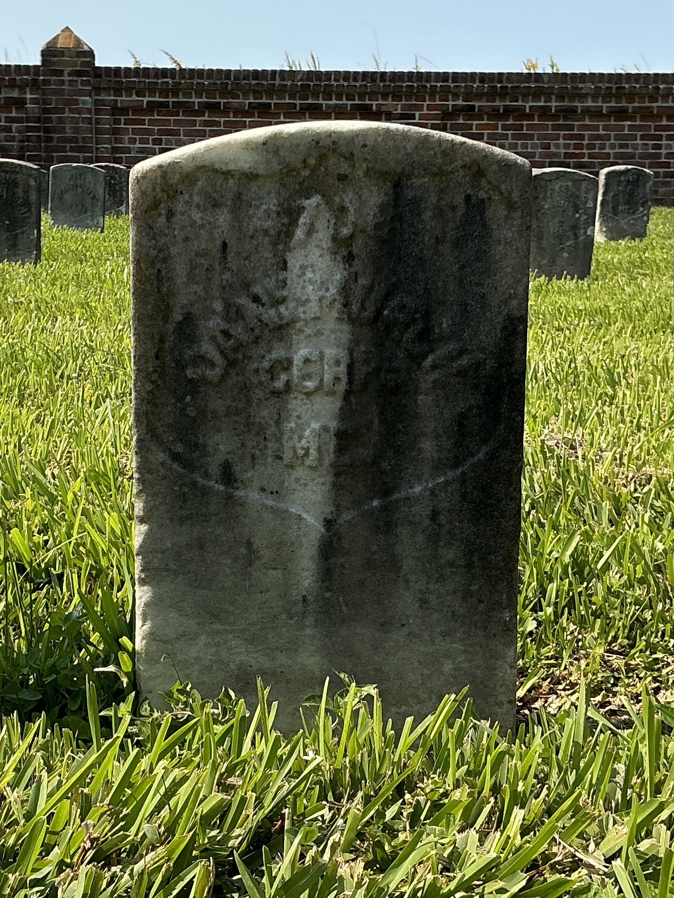 Front of historic upright marble headstone with recessed shield face.
