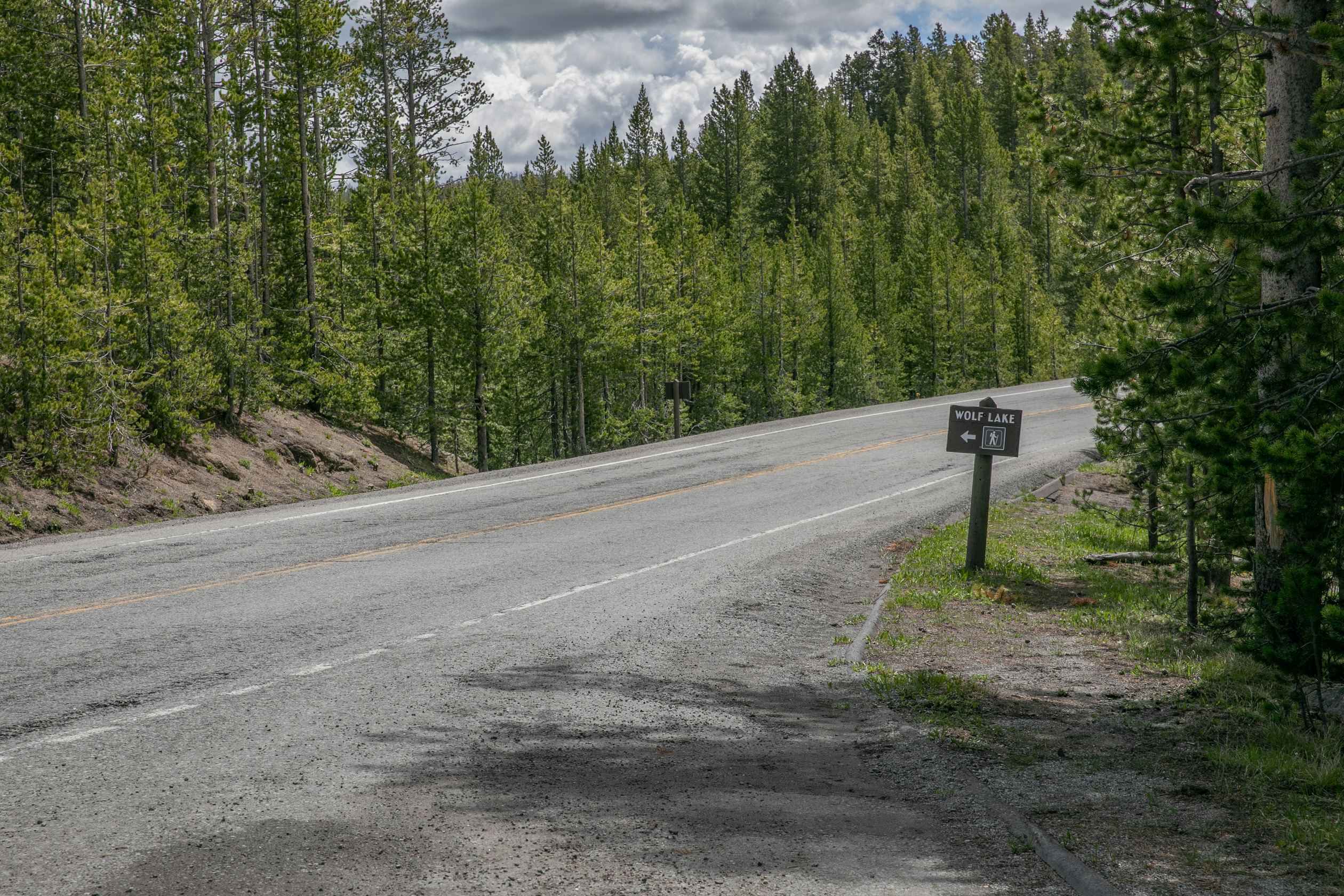 A sign points across the road to the trail.