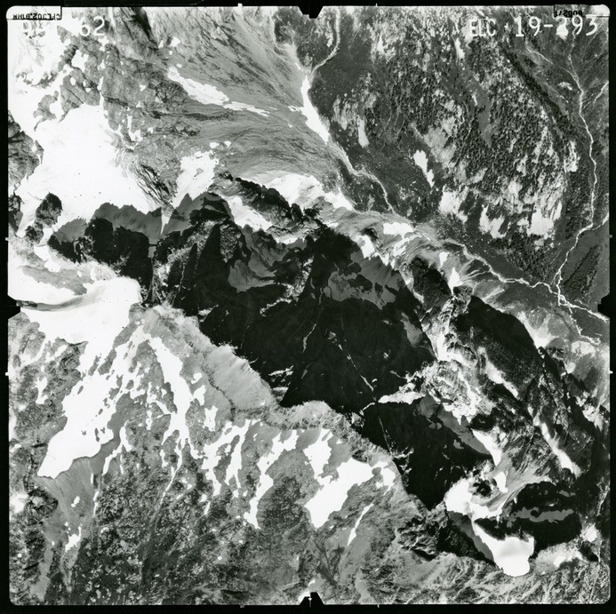 Black and white aerial photograph of glaciated mountain peaks and valleys.