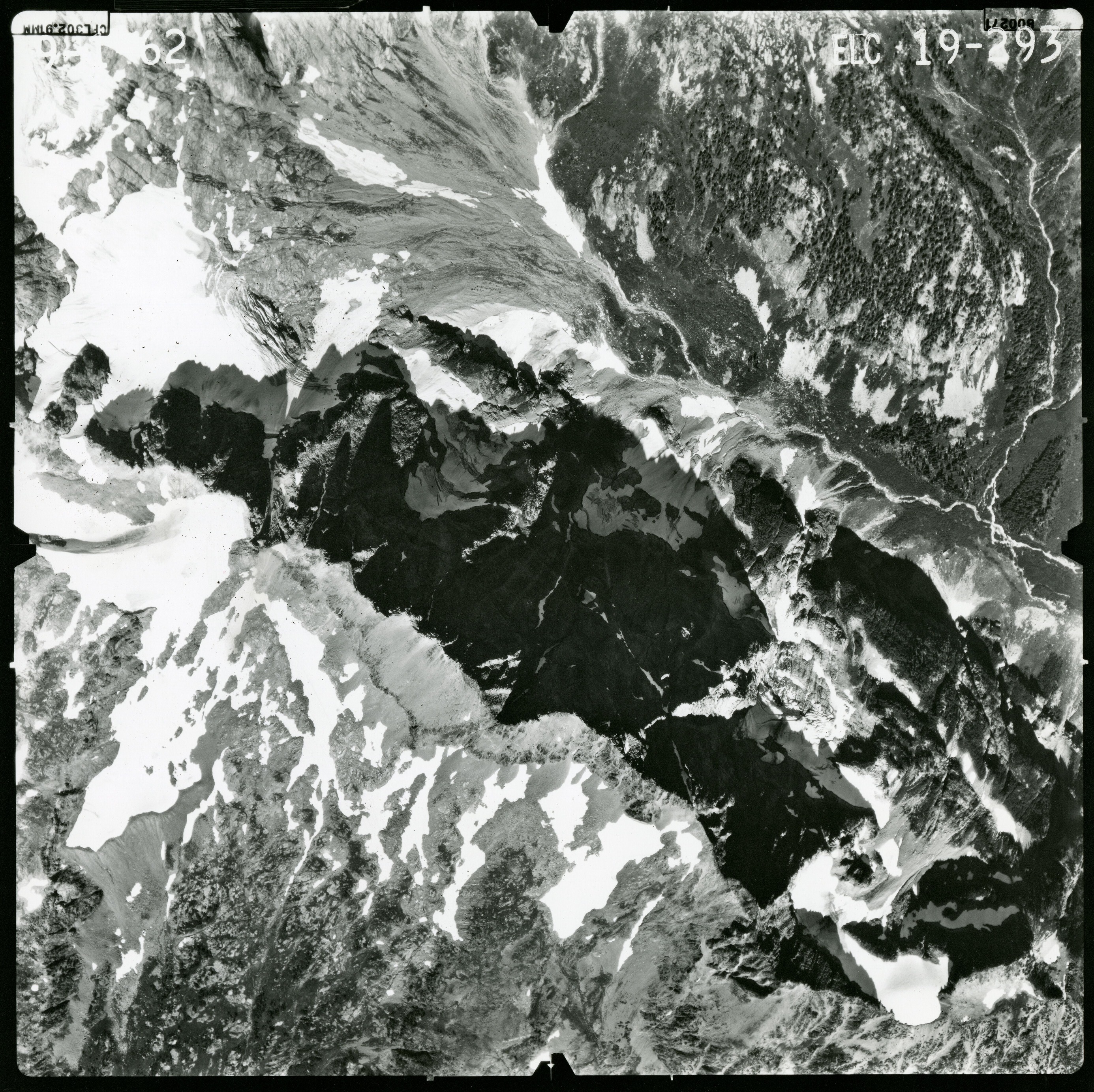 Black and white aerial photograph of glaciated mountain peaks and valleys.