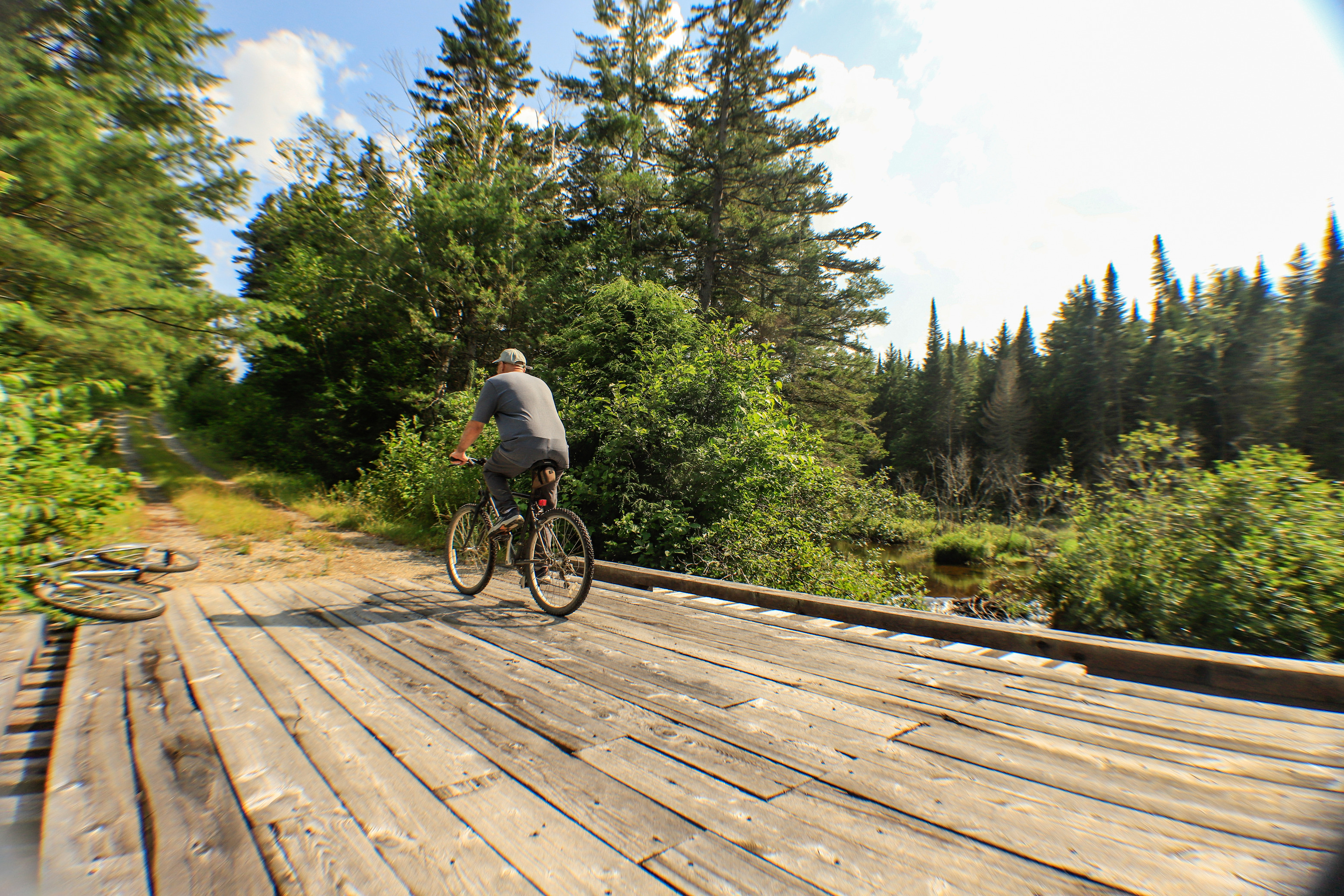 Cyclist biking away from the camera across a wide wooden bridge