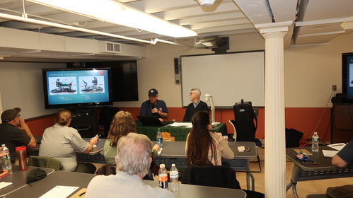 Two men address a classroom.