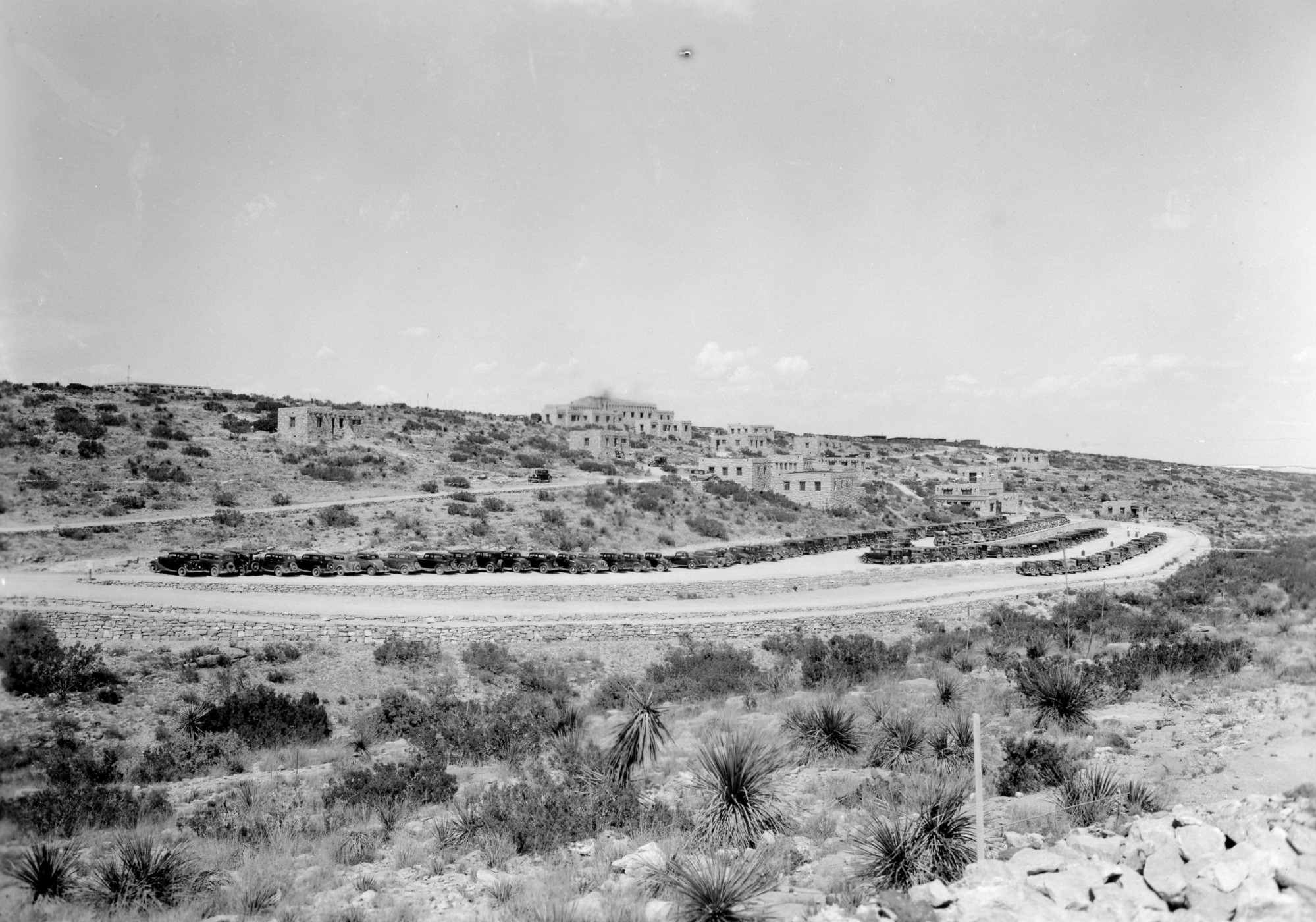 A black and white photograph of the original parking lot filled with cars. Ranger residences can also be seen dotted along the terrain.