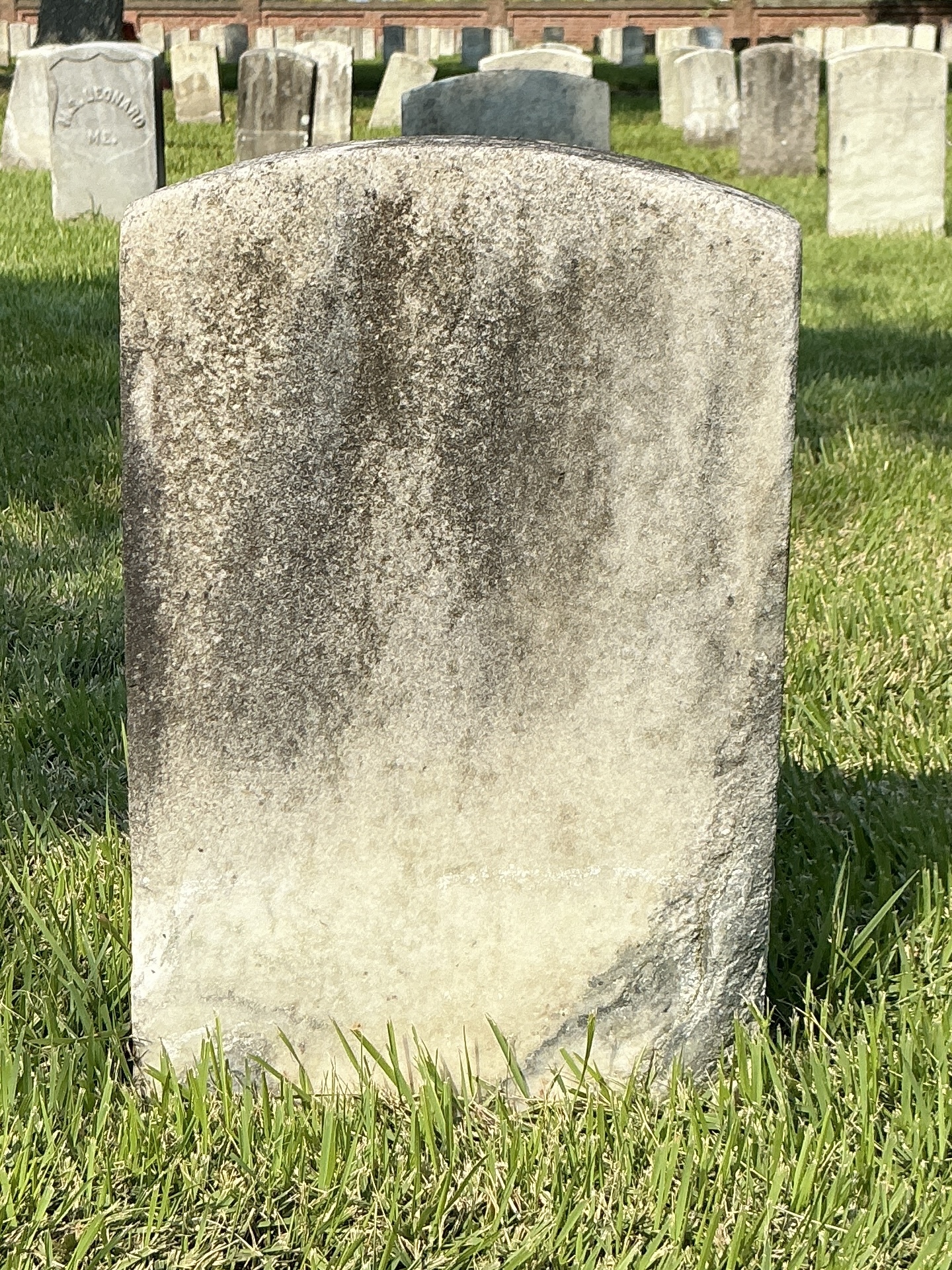 Back of historic upright marble headstone with recessed shield face.