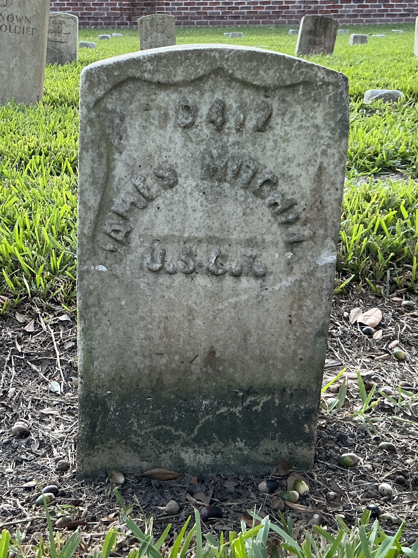 Front of historic upright marble headstone with recessed shield with recessed lettering face.
