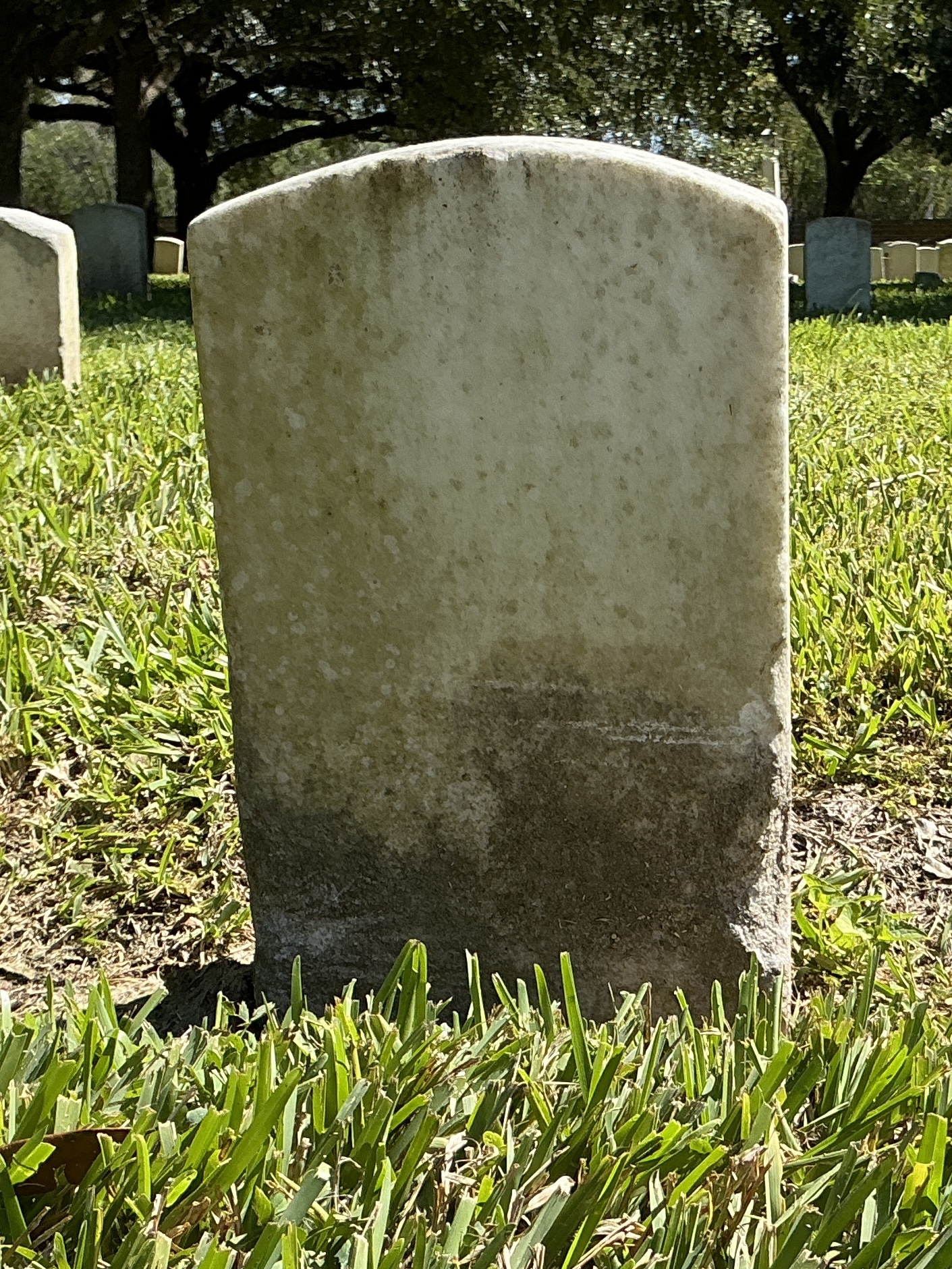 Back of historic upright marble headstone with recessed shield face.