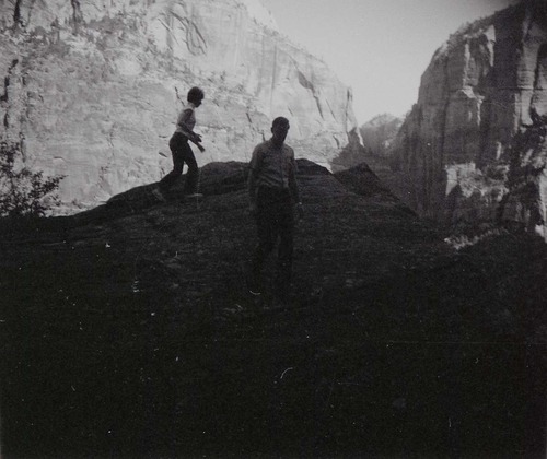 Man and woman on slickrock near water tanks involved in reroofing project.