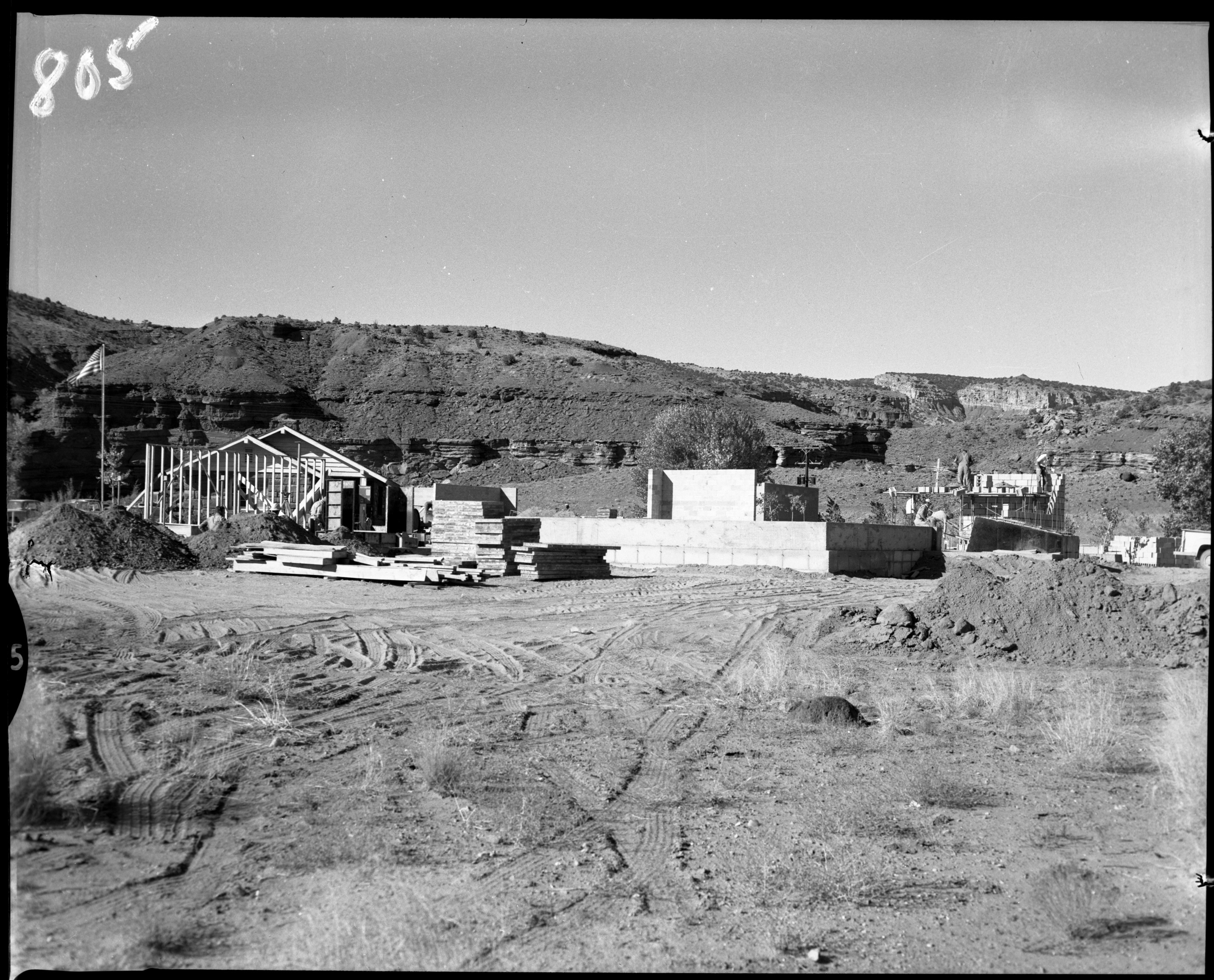 Building frame, cinderblocks, and American flag flying. 