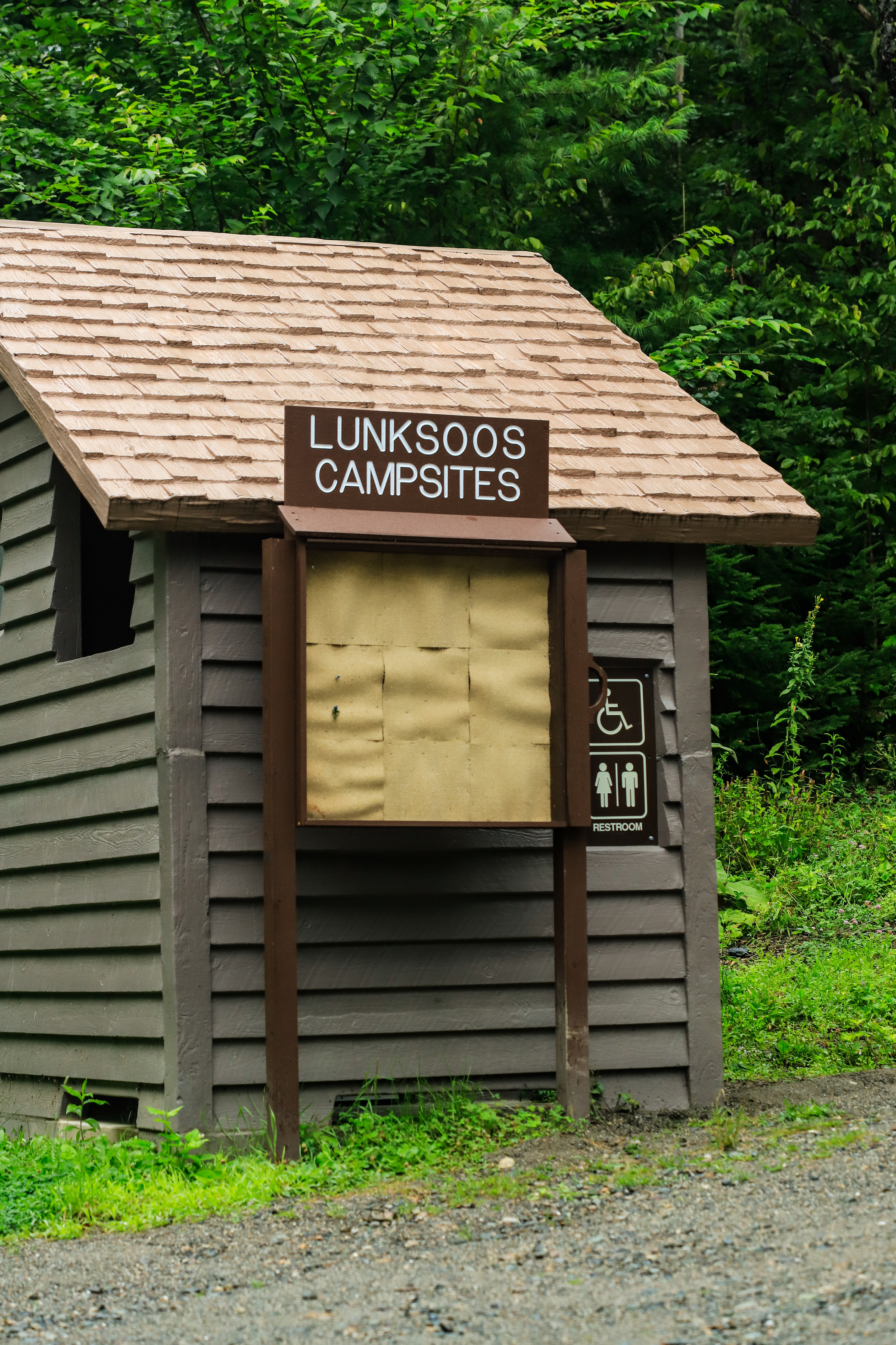 A Lunksoos Campsite post sign in front of an outhouse