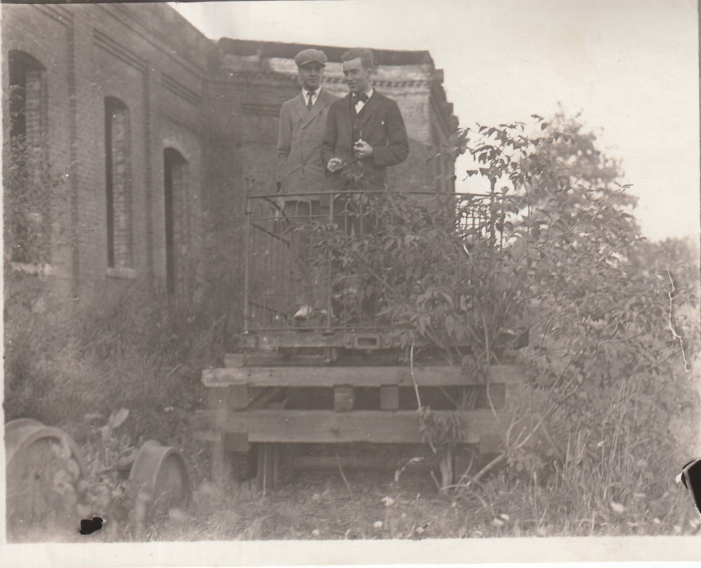 Theodore and Charles Edison standing atop "trailer" used for electric locomotive, near machine shop at Menlo Park lab.
