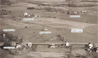 A black and white aerial photo of land with 6 labels. The labels read from left to right, MD Monument, Dunker Church, Mumma Farm, NY Monument, Roulette Farm, Location of the Visitor Center