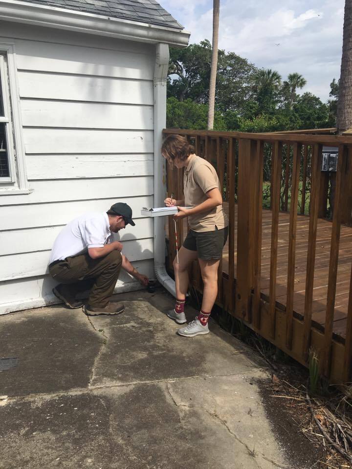 two researchers one kneeling and other with clipboard