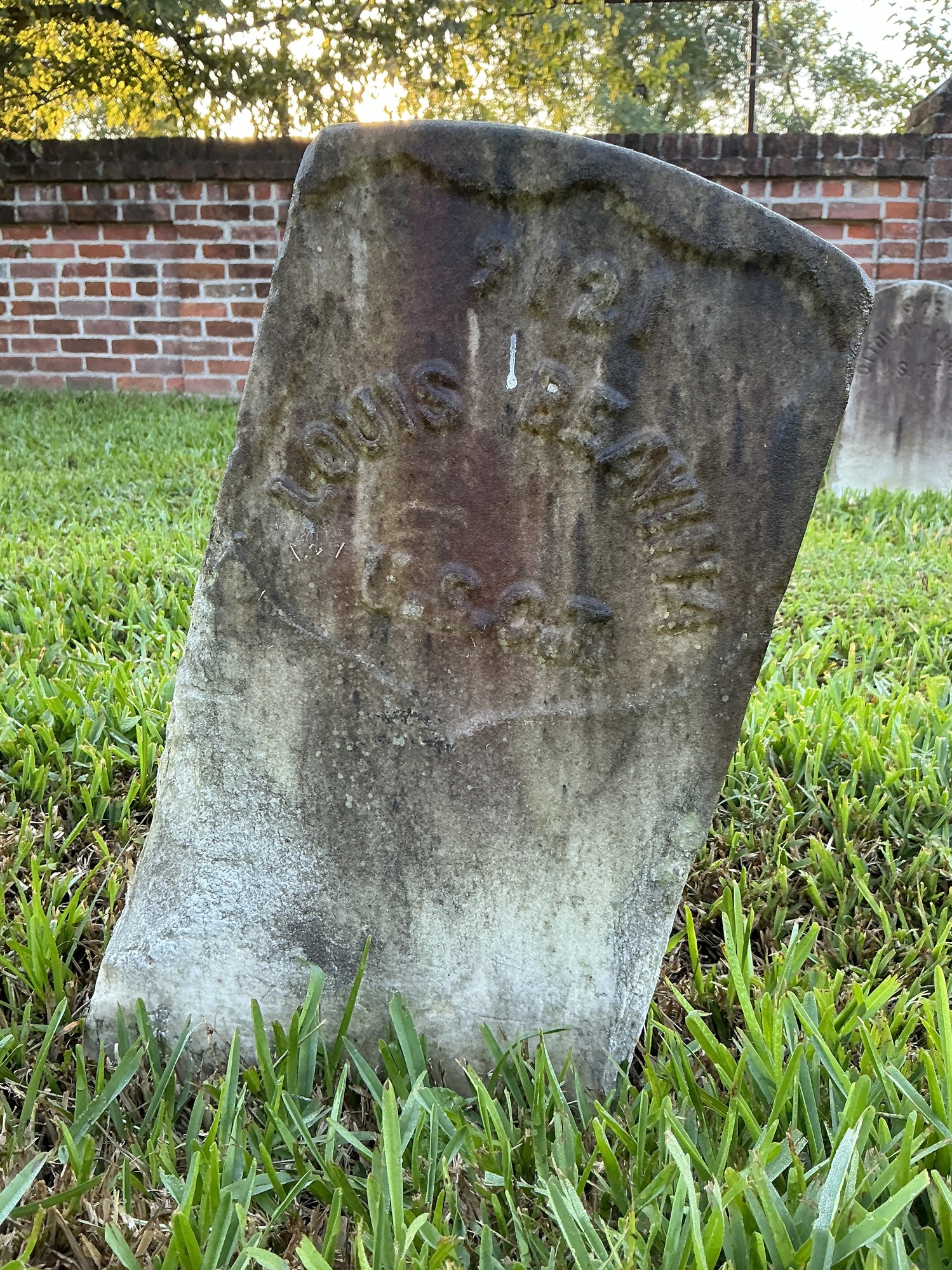 Front of historic upright marble headstone with recessed shield face.