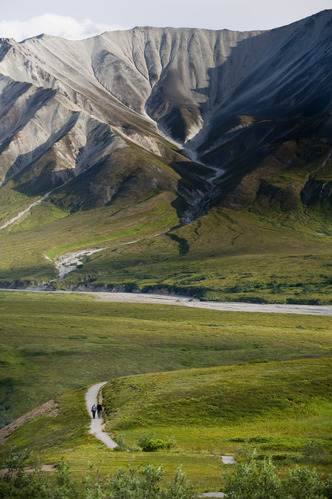 two people walking a trail on a tundra hillside