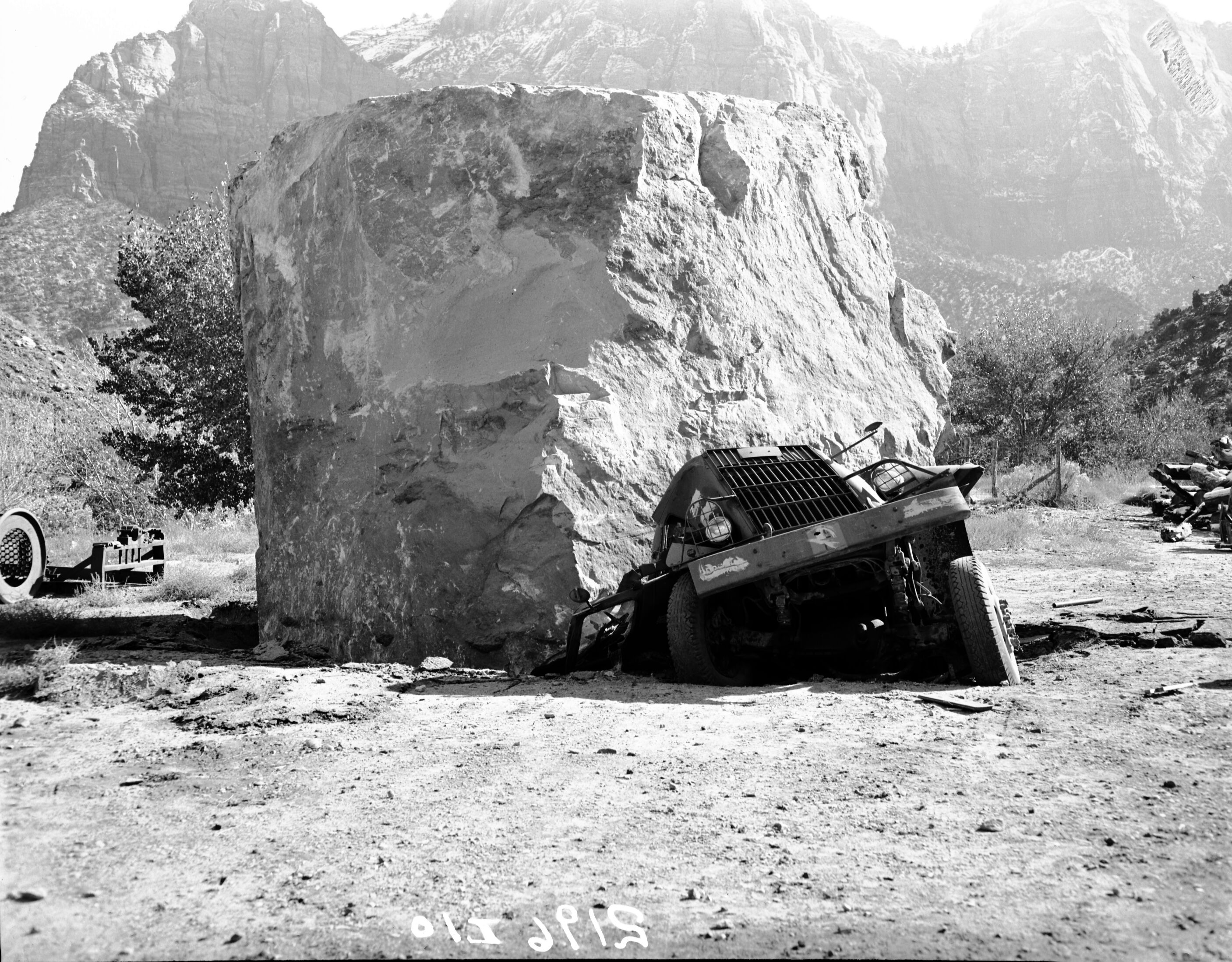 Rock slide of November 23, 1947. Utility yard. Boulder lodged in front of stone bridge, rolled more than 1000 feet from ledge. Marjorie Walker standing on boulder.