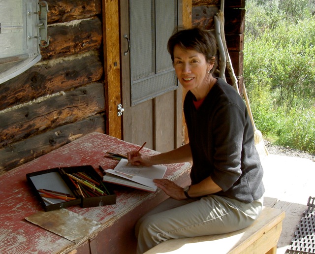 woman outside a log cabin writing in a journal