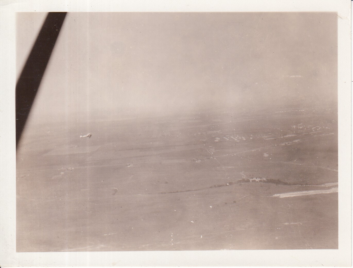 Aerial view of unidentified location, airplane visible in sky.
