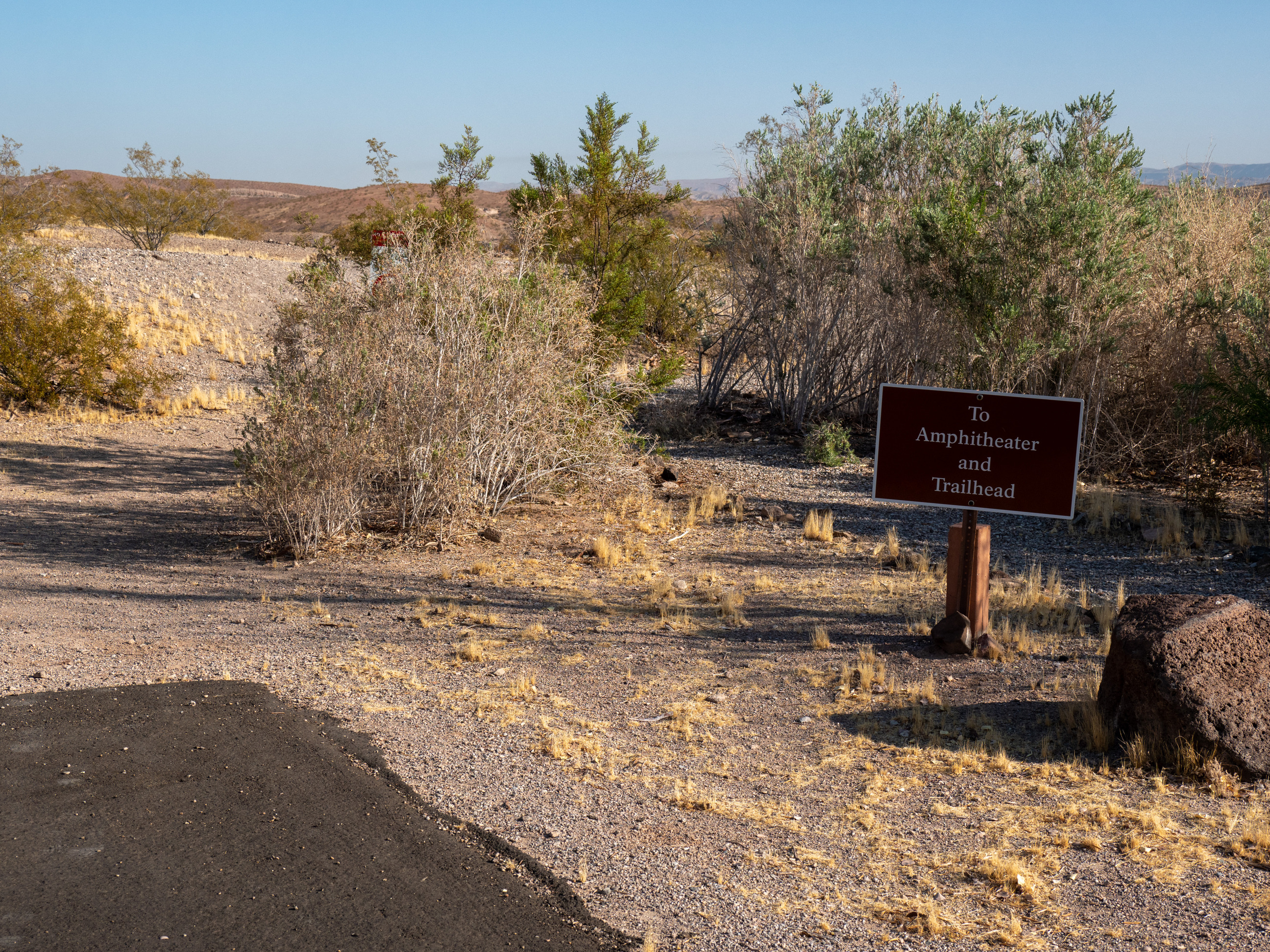 desert bushes, sign at right reads, to amphitheater and trailhead