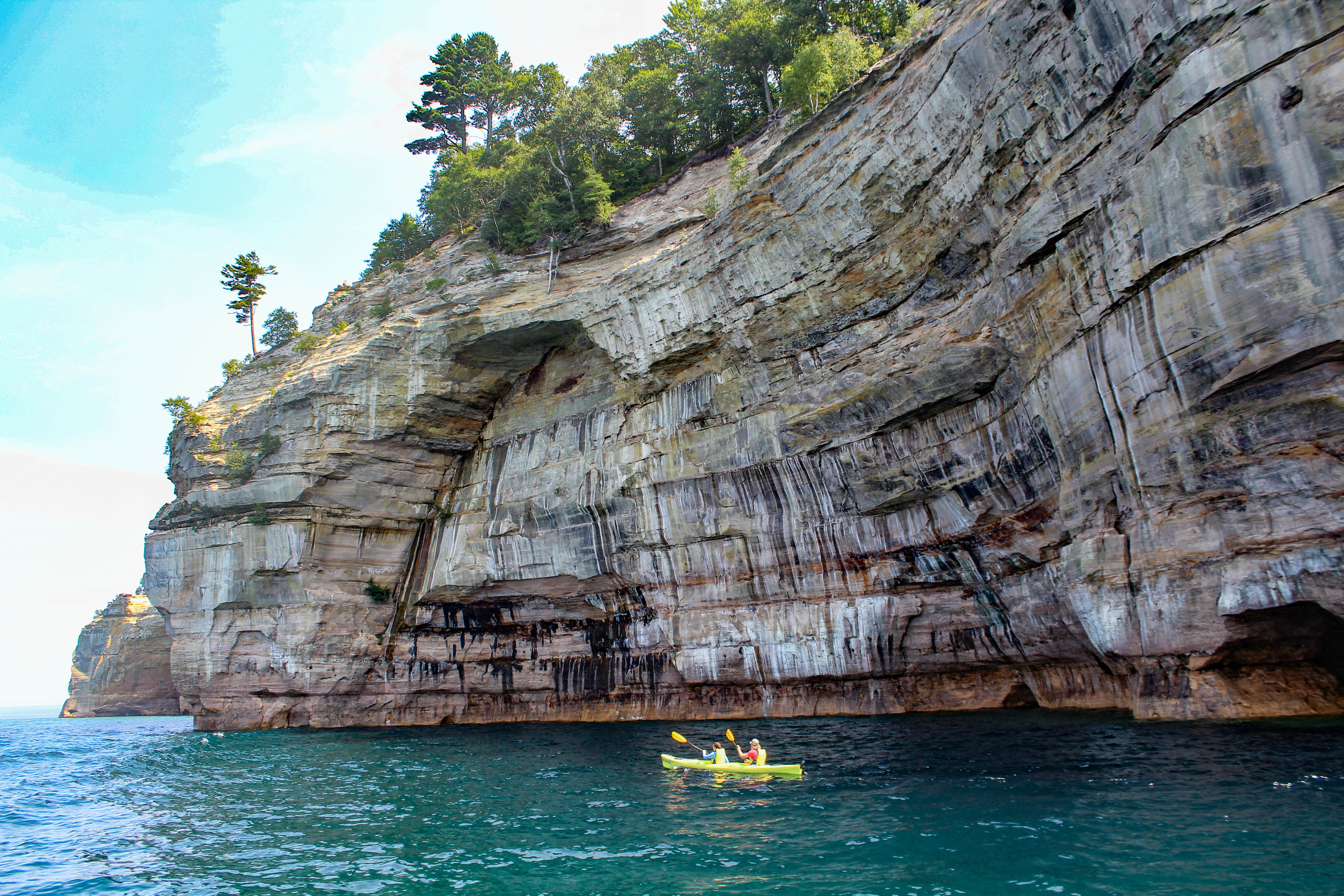 Kayakers paddling along tall cliff faces